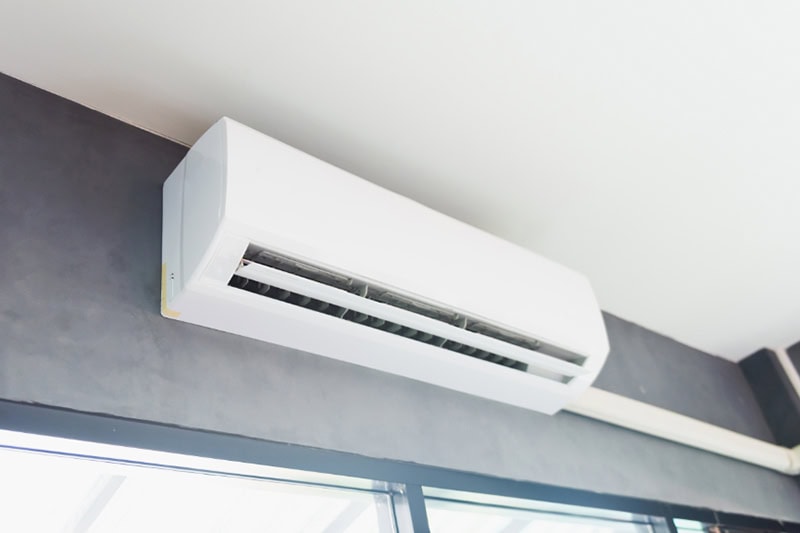 How to Cool the Upstairs of a Two-Story Home. Photo of a ductless air conditioning mounted on a wall.